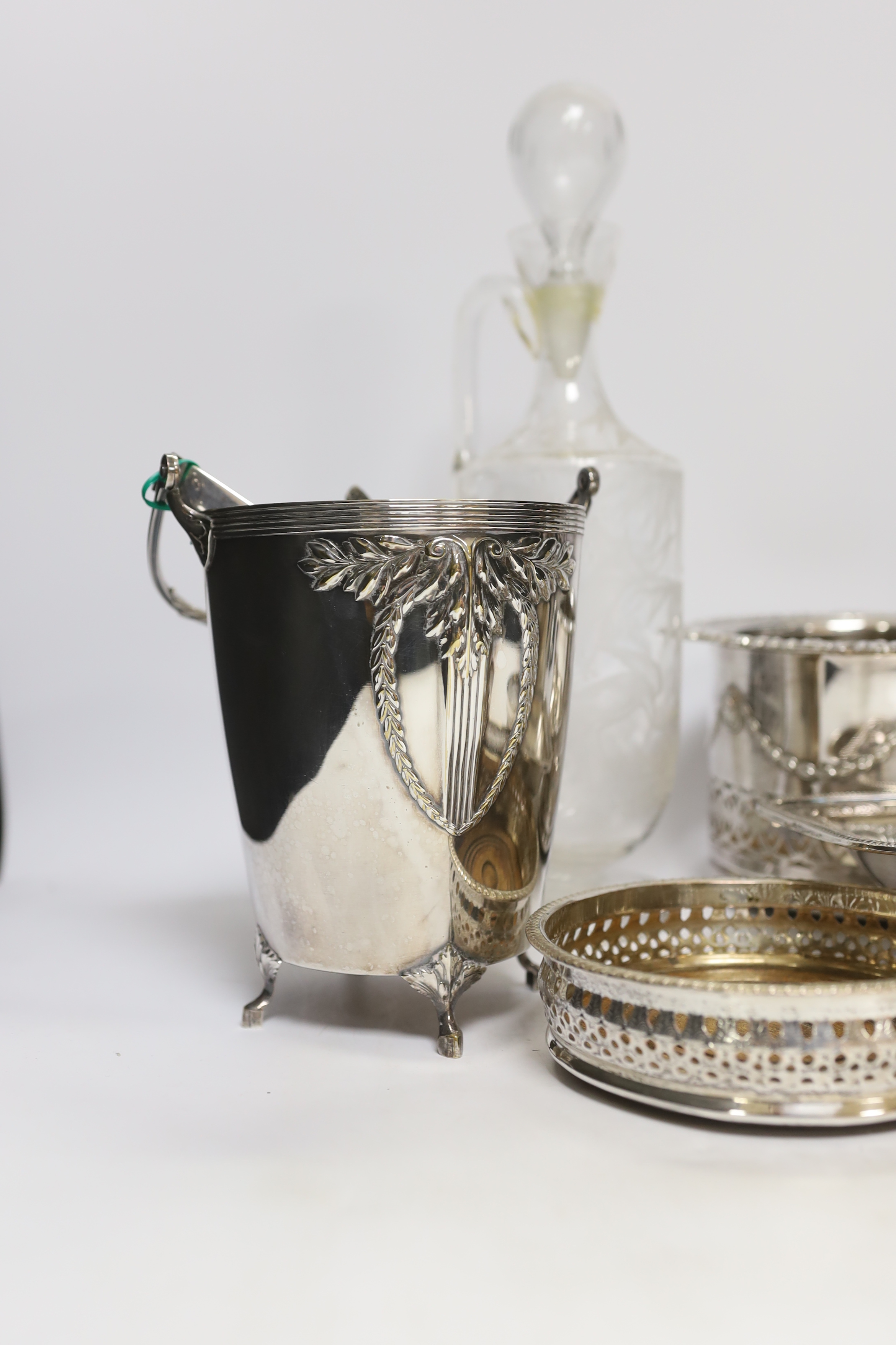 Two decanters; one with silver mount and one with etched body, together four wine coasters, a bucket raised on four feet, etc.